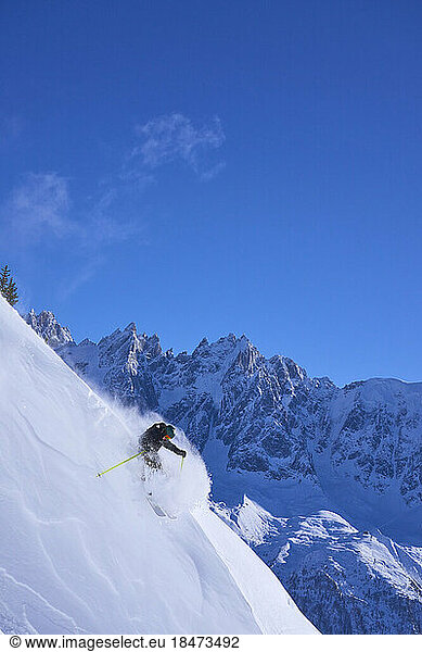 Man skiing downhill under blue sky