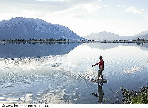Man skips rock from island  mountains distant