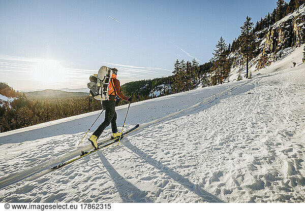 Man skis along wintery snowy trail at sunrise near Crater Lake  Oregon