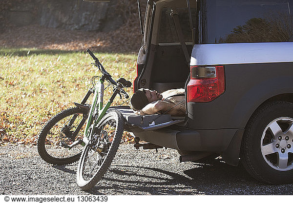 Man sleeping in car trunk by mountain bike