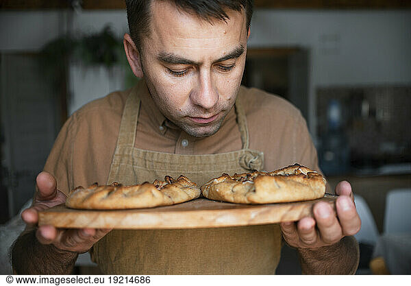Man smelling baked pie on cutting board