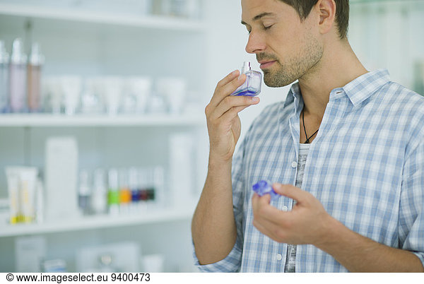 Man smelling perfume in drugstore