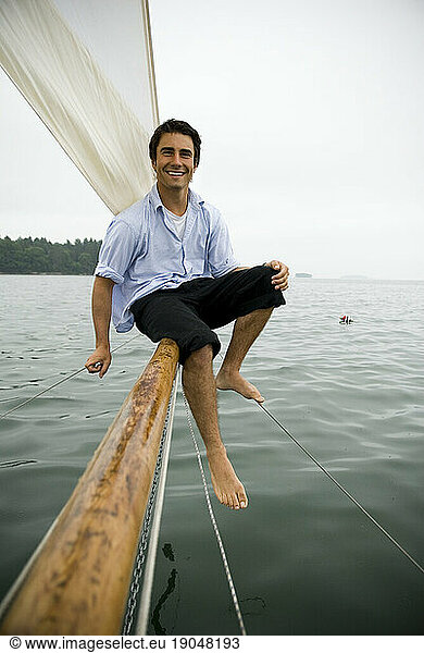 Man smiling on bowsprit of sailboat  Casco Bay  Maine  New England.
