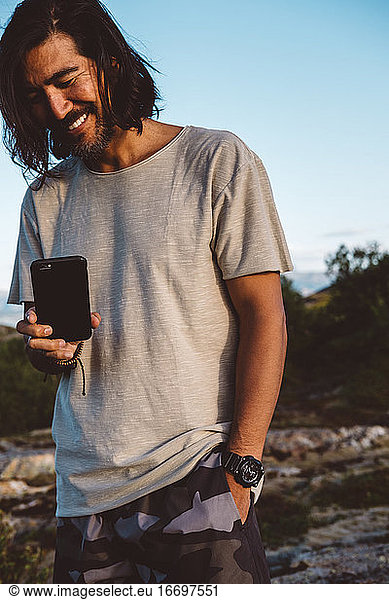 Man smiling taking a photo with his smartphone outdoors
