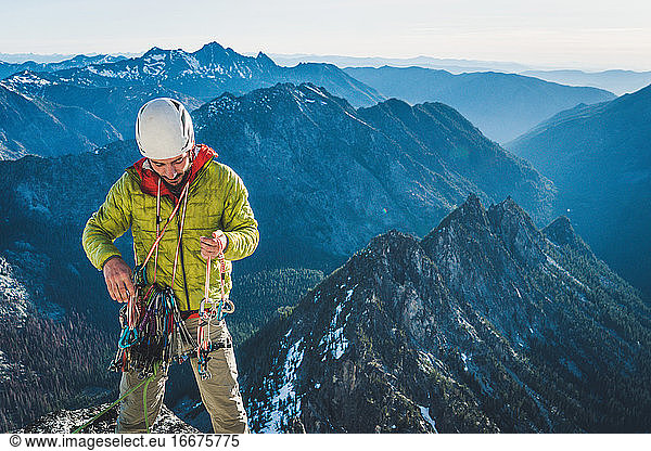 Man sorting climbing gear on alpine rock climb in Washington