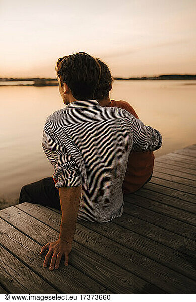 Man spending leisure time with boyfriend while sitting on pier