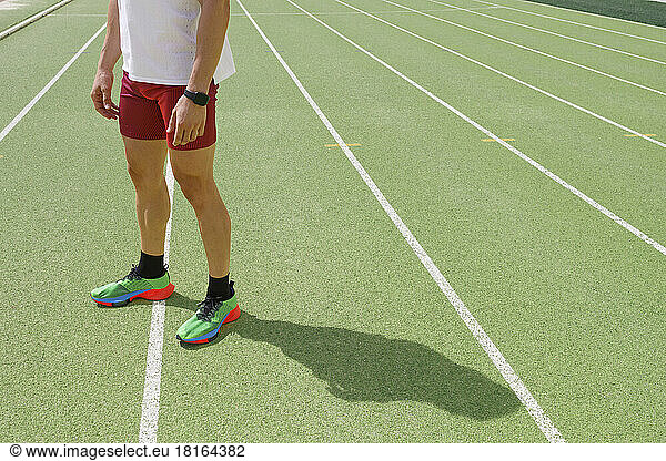 Man standing at sports track on sunny day