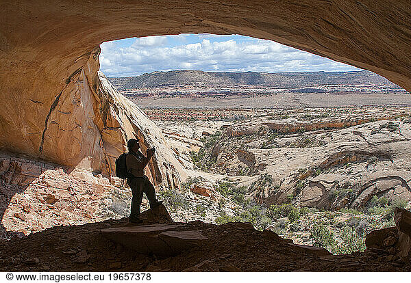 Man standing in Fishmouth Cave  Comb Ridge in Butler Wash  Bears Ears National Monument  Utah  USA