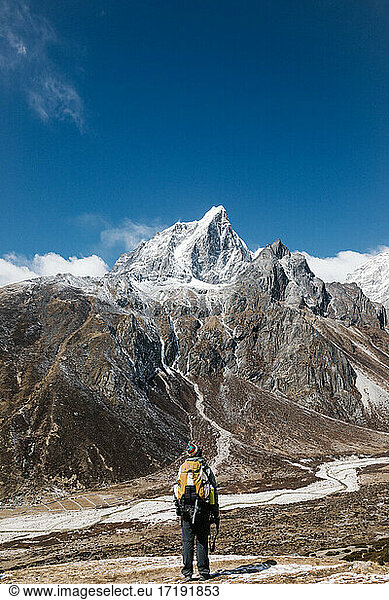 Man standing in front of a snow capped mountain  HImalayas  Nepal