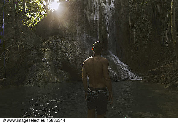 Man standing near waterfall