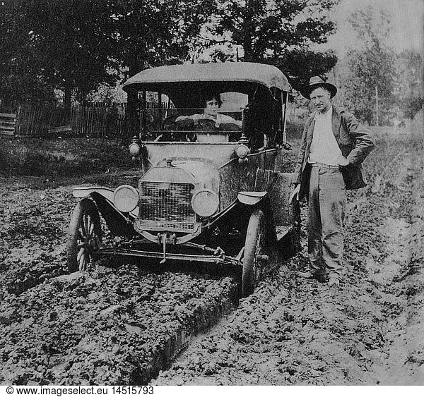 Man Standing Next to Woman in Ford Model T Car on Muddy Road  Early 1900's