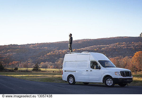 Man standing on camper van against clear sky