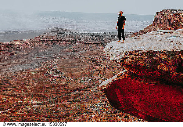 Man standing on the edge of a large cliff with open views
