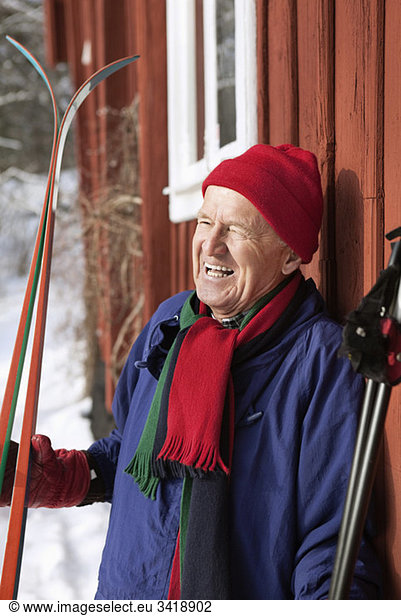 Man standing outdoors holding skis