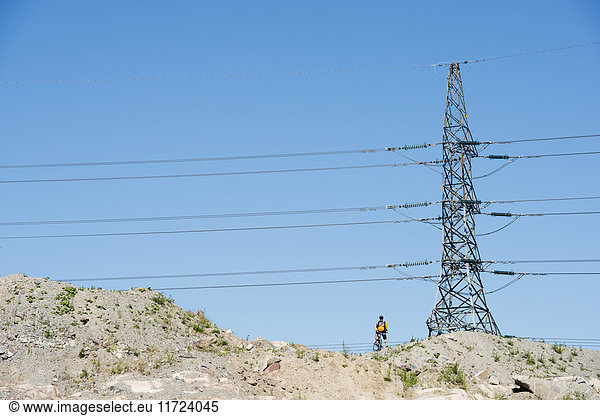 Man standing under electricity pylon