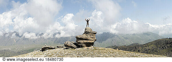 Man standing with arms raised at Mount Elbrus under cloudy sky  Caucasus