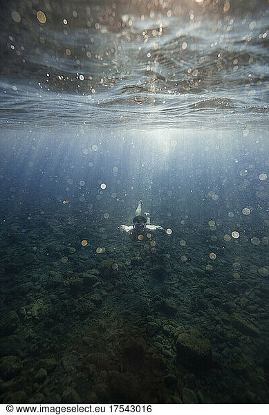 Man swimming over ocean floor undersea