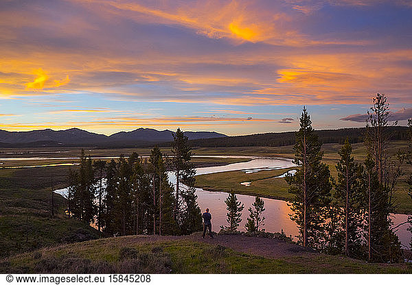Man taking a photo at Yellowstone River in Hayden Valley at sunset