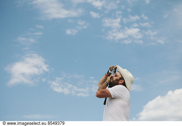 Man taking a photograph of clouds and sky.