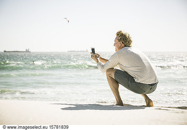 Man taking a smartphone picture on the beach