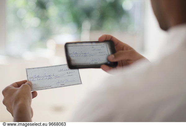Man taking photo of banking check with cell phone