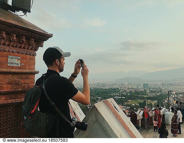 Man taking picture on phone overlooking city in Nepal