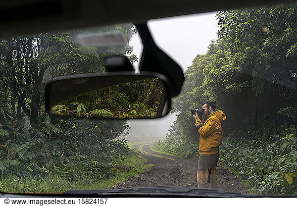 Man taking picture outside car on forest road  Sao Miguel Island  Azores  Portugal