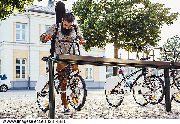 Man taking rental bicycle off rack at station