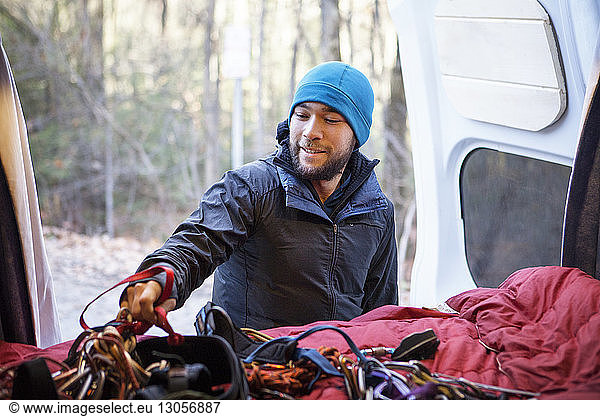 Man taking rock climbing equipment from camper van
