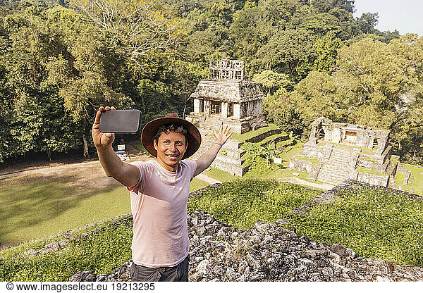Man taking selfie with smart phone in front of Mayan ruins