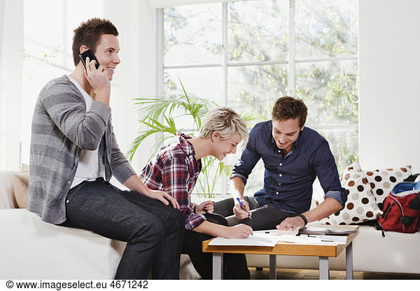 Man talking int telephone  two friends looking at papers