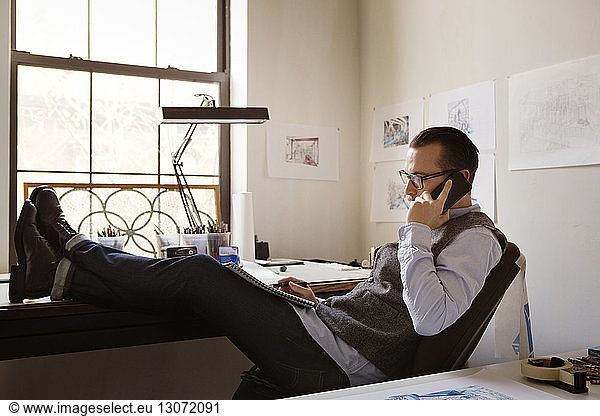 Man talking on phone while sitting at art studio