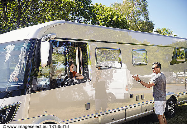 Man talking to woman sitting in motor home during summer vacation