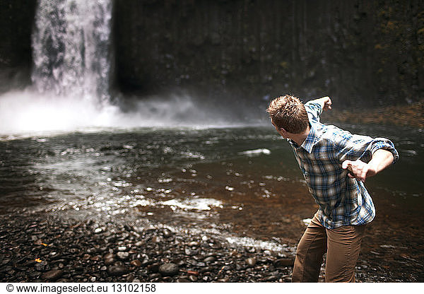 Man throwing stone at waterfall