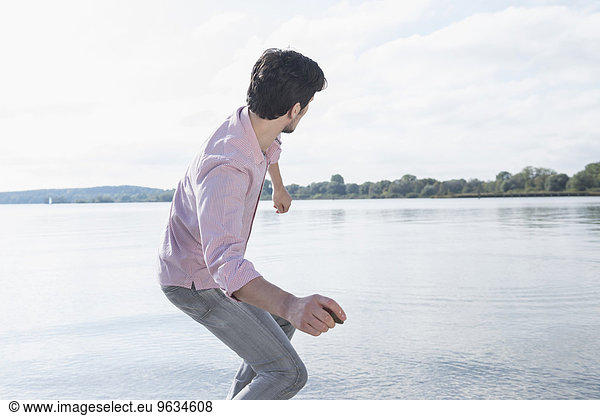 Man throwing stone water lake fun