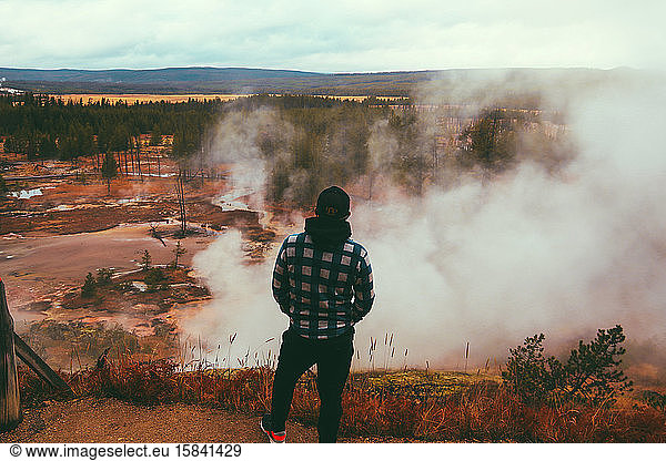 Man tourist overlooking geyser at Yellowstone National Park