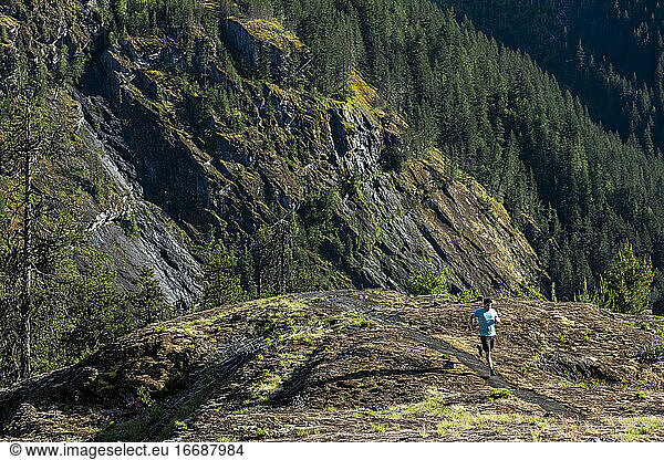 Man trail runs on a scenic alpine mountain trail in British Columbia.