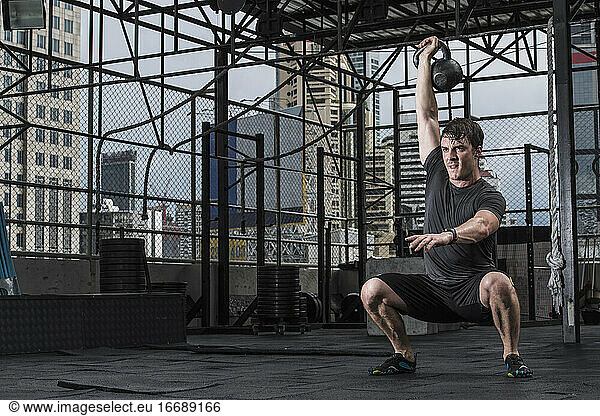 man training with kettle bell at rooftop gym in Bangkok