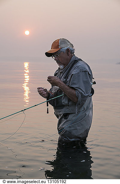Man tying a fly on his fly fishing line while fishing for salmon and searun cutthroat trout