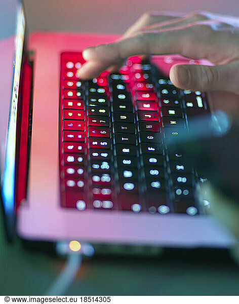Man typing on illuminated keyboard at office