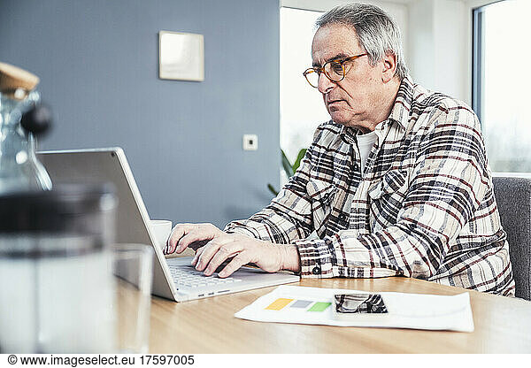 Man typing on laptop sitting at table
