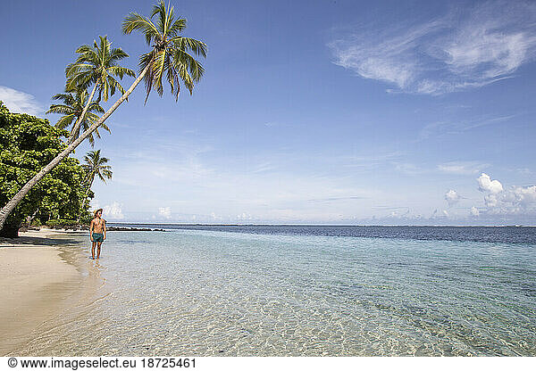Man under leaning palm tree  at idyllic beach of South Pacific  Samoa