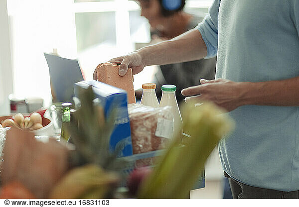 Man unloading grocery delivery at kitchen counter