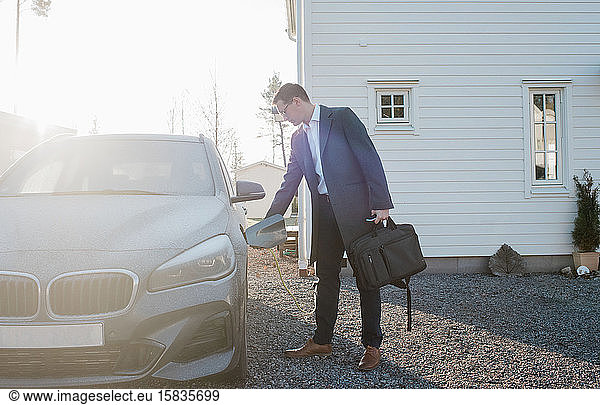 man unplugging his electric car ready to leave for work from home