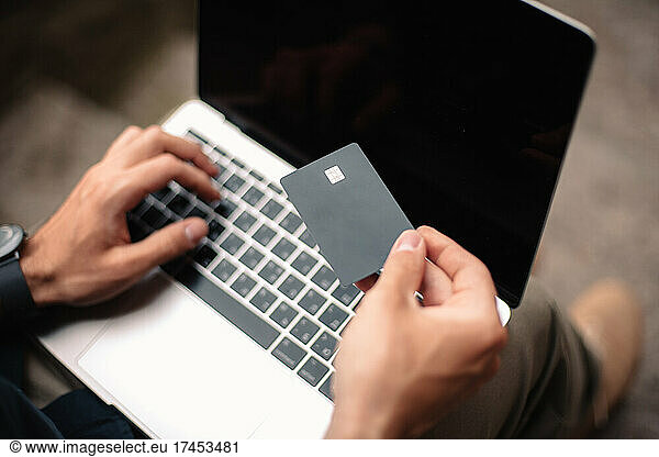Man using credit card and laptop computer while shopping online