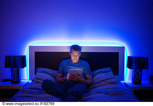 Man using digital tablet in bed