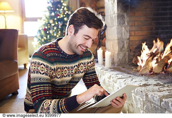 Man using digital tablet in front of fireplace