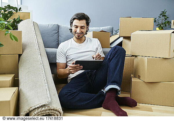 Man using graphic tablet amidst cardboard boxes at home