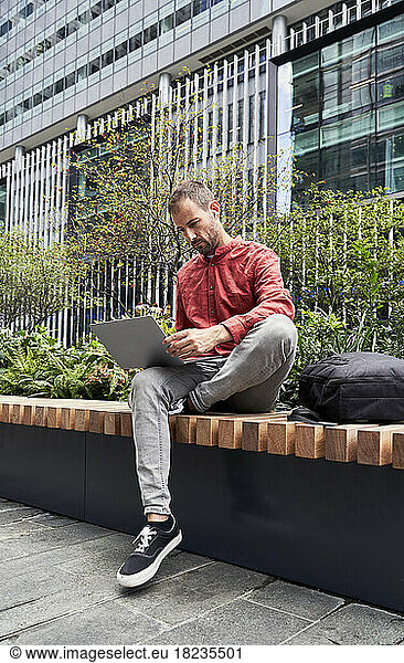 Man using laptop on bench