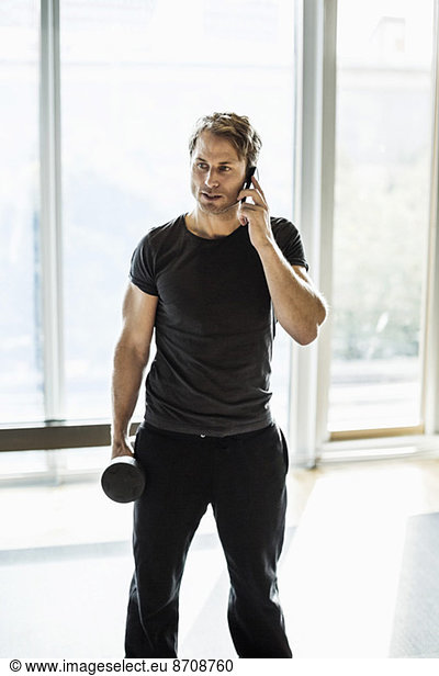 Man using mobile phone while exercising at gym